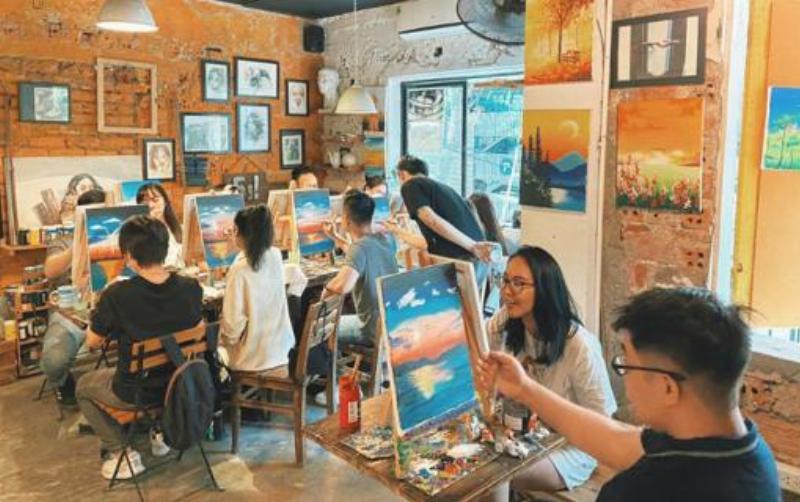 Một nhóm người đang tham gia buổi workshop cắm hoa tại một shop hoa, mọi người đều vui vẻ và tập trung